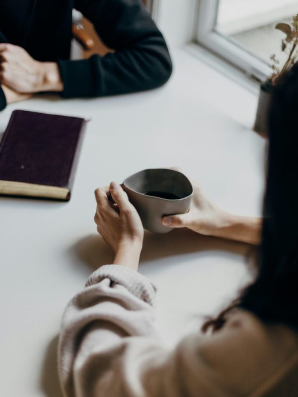 A counselling session, only arms and hands visible, at a table. By Priscilla du Preez