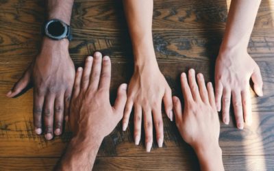 Five hands meeting on an old wood table.